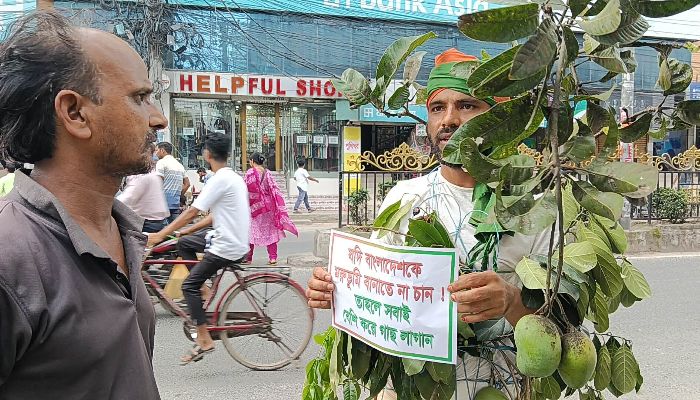 তপ্ত রোদে সড়কে দাঁড়িয়ে জীবন্ত গাছ হয়ে সচেতনতার বার্তা ছড়াচ্ছেন রেজা
